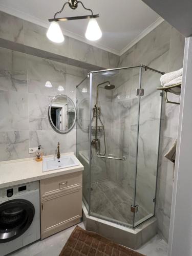 ein Bad mit einer Dusche und einem Waschbecken in der Unterkunft Уютная квартира in Bischkek