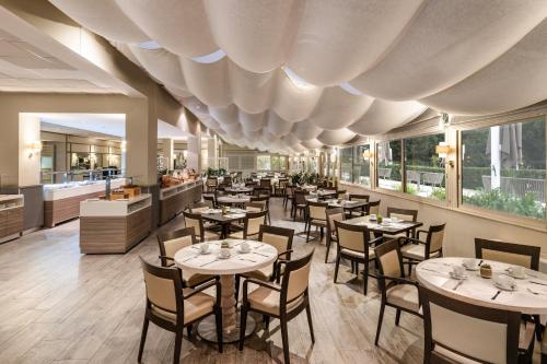 un restaurant avec des tables, des chaises et des fenêtres dans l'établissement Crowne Plaza Rome St. Peter's by IHG, à Rome