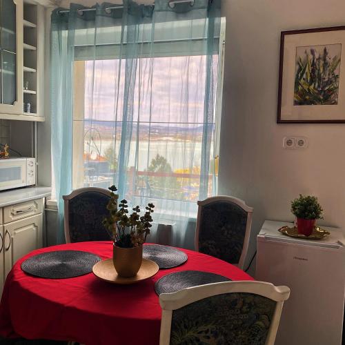 a dining room table with a red table cloth and a window at Villa Borostyán in Tihany