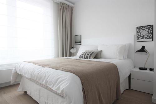 a white bedroom with a large bed and a window at Superbe appartement neuf à Liège Guillemins in Liège