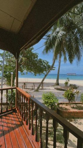 a balcony with a view of a beach with palm trees at SALANG SAYANG RESORT , PULAU TIOMAN in Tioman Island