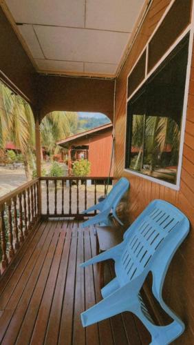 SALANG SAYANG RESORT , PULAU TIOMAN في جزيرة تيومان: كرسيان زرقان يجلسون على شرفة المنزل