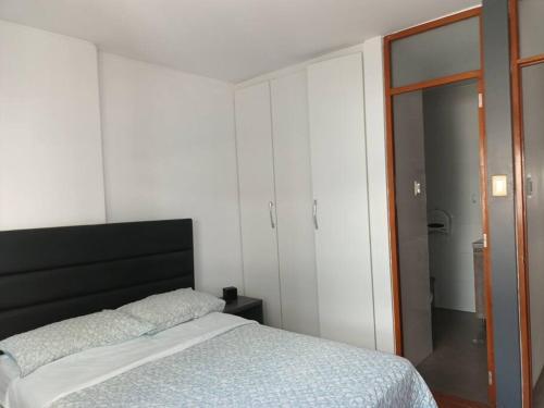 Schlafzimmer mit einem Bett mit einem schwarzen Kopfteil in der Unterkunft Estadía Palmira, Moderno departamento 2 piso in Chiclayo