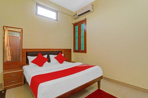 1 dormitorio con 1 cama grande con almohadas rojas en OYO Flagship Kk Guest House, en Hasanganj