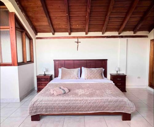 Un dormitorio con una cama grande con una cruz. en Casa de campo acogedora con WIFI- ZONA BBQ- PARQUEO, en Loja