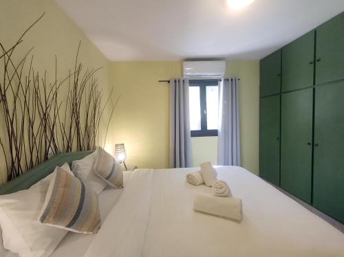 Un dormitorio con una cama blanca con toallas. en Summer Dream Cottage, 2BR, Beautiful sea view, en Mókhlos