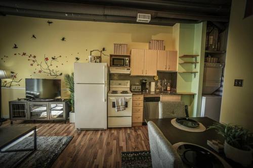 a kitchen with a white refrigerator and a table at 2 Full Beds, Rogers Place Downtown Central, Memorable 1 Bedroom Condo in Edmonton