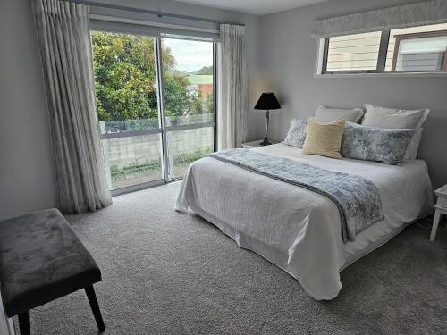 a bedroom with a bed and a large window at Delightful Petone Townhouse in Lower Hutt
