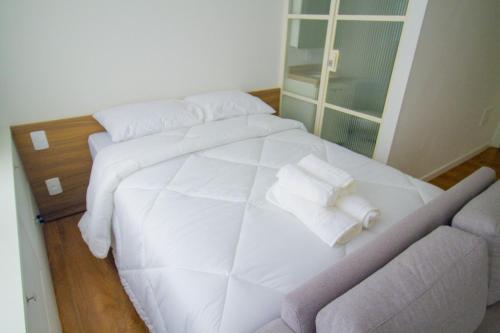 a white bed in a room with a couch at Blend Coliving One - 2a in Ribeirão Preto