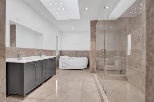 a bathroom with a tub and a sink and a shower at 5000 Square Ft Beautiful Mansion w 6br Hot Tub Playground Movie Theater & Game Room in Dania Beach