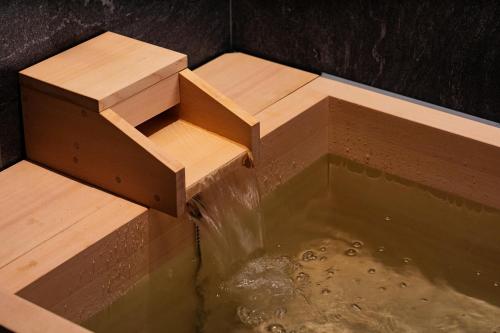 a water fall with a wooden bench in a pool of water at SHIROIYA HOTEL in Maebashi