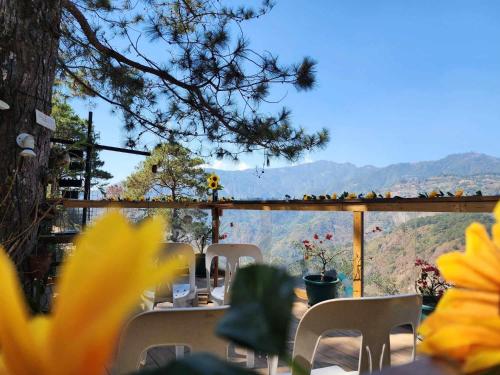 a table with white chairs and a view of the mountains at Wood and Mountain in Baguio