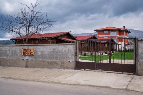 a fence in front of a house with a building at Къщи за гости БРИК in Sapareva Banya