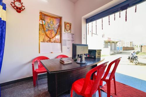 ein Büro mit roten Stühlen und einem Schreibtisch mit einem Computer in der Unterkunft SPOT ON Devlok Guest House in Patna