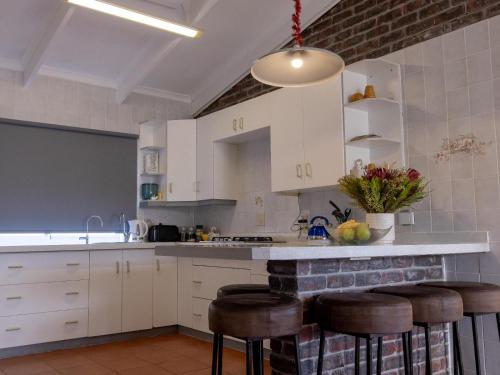 a kitchen with white cabinets and bar stools at The Yellow Door in De Kelders