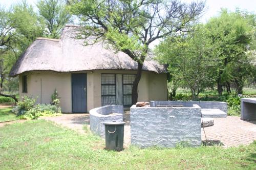 a small house with a thatched roof and a trash can at Grootgeluk in Naboomspruit
