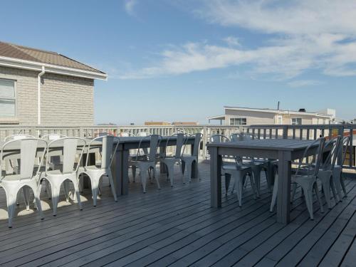 a wooden deck with a table and chairs on it at The Yellow Door in De Kelders