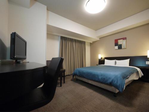 a hotel room with a bed and a flat screen tv at Hotel Route-Inn Hisai Inter in Tsu