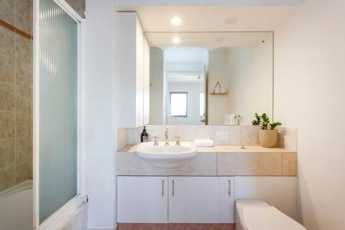 Baño blanco con lavabo y espejo en Suffolk Villa Fremantle On Your Doorstep, en Fremantle
