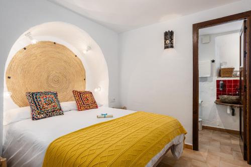 a bedroom with a bed with a yellow blanket at Casa Lunarito in Vejer de la Frontera