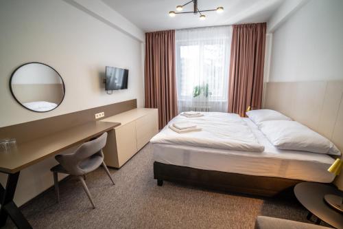 a hotel room with a bed and a desk and a mirror at Hotelový Dům in Olomouc