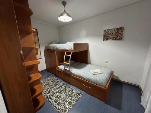 um pequeno quarto com um beliche e uma cadeira em El pisuco em Sarón