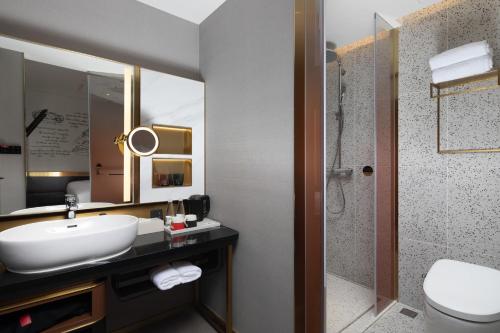 W łazience znajduje się umywalka, toaleta i lustro. w obiekcie Shenzhen Futian Xiameilin Metro Station CitiGO Hotel w mieście Shenzhen