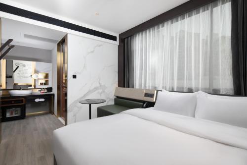 a bedroom with a large white bed and a desk at Shenzhen Futian Xiameilin Metro Station CitiGO Hotel in Shenzhen