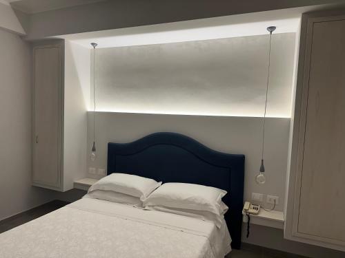 a bedroom with a bed with a blue headboard at Hotel Mediterraneo in Roccella Ionica