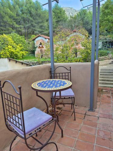 une table et deux chaises assises sur une terrasse couverte dans l'établissement Gîte dans Bastide Provençale, Piscine & Sauna, à Auriol