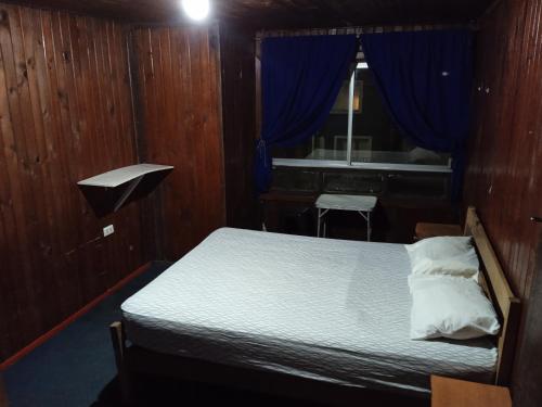 1 dormitorio con 1 cama con cortinas azules y espejo en Pensión Las Salinas, en Talcahuano