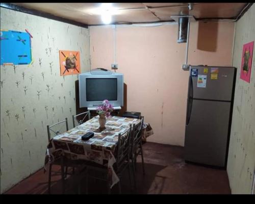 Habitación con mesa, TV y nevera. en Pensión Las Salinas, en Talcahuano