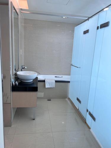 a white bathroom with a sink and a tub at Golden Tulip Zhong Xin Hotel Taichung in Taichung
