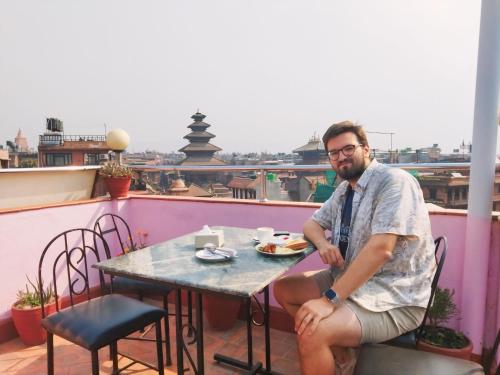a man sitting at a table on a balcony at HOTEL RUPAKOT AND ROOFTOP RESTAURANT in Bhaktapur