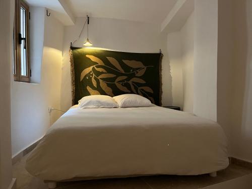 - une chambre avec un grand lit blanc orné d'une peinture murale dans l'établissement Casa Moncollet, à Roquebrune-Cap-Martin