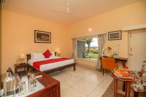a bedroom with a bed and a desk and a window at Amritara Jawai Resort in Pāli