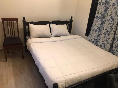 a bed with white sheets and a chair in a room at Continental 'LeBe INN in Tirupporūr