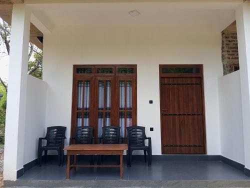 a group of chairs and a wooden table and doors at River Nature Park in Polonnaruwa