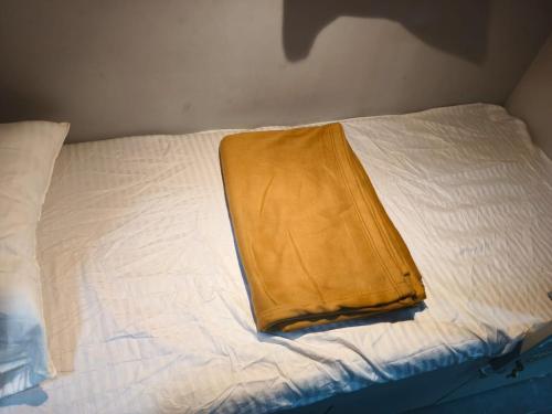 ein weißes Bett mit einer gelben Decke drauf in der Unterkunft Rest Inn Hostel Dormitory in Mumbai