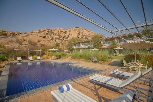 a swimming pool with chairs and a mountain in the background at Amritara Jawai Resort in Pāli