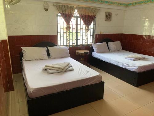 Duas camas num quarto com janelas em Ditar Guest House D em Battambang