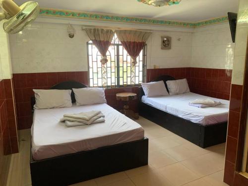 two beds sitting in a room with windows at Ditar Guest House D in Battambang