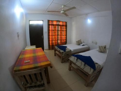 Cette chambre comprend 2 lits, une table et une fenêtre. dans l'établissement DEEP SEA RESORT PADI DIVE CENTER, à Amirthakaly