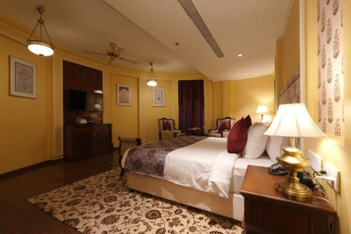a hotel room with a bed and a table with a lamp at The Garden Ananta Elite in Rajkot