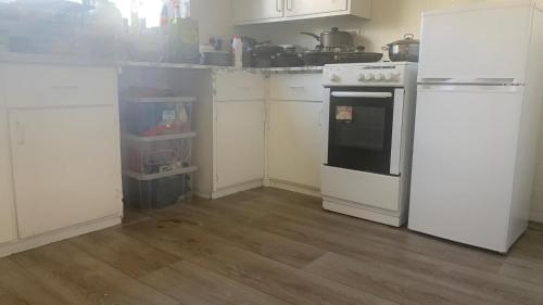 a kitchen with white cabinets and an oven in it at Beautiful Bedroom near Barking Railway station in london with good Transport Link direct connect with central london in Barking