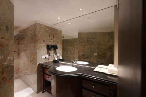 a bathroom with a sink and a large mirror at The Garden Ananta Elite in Rajkot