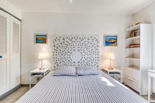 a white bedroom with a bed and two lamps at Les Palmiers in Palavas-les-Flots