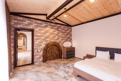 a bedroom with a bed and a brick wall at Aynur Qala Resort in Quba