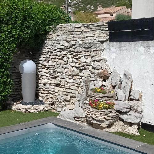 een stenen muur en een zwembad in een tuin bij Chez Nous in Le Rove
