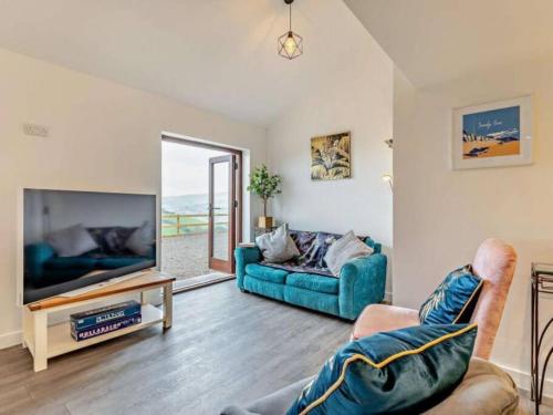 a living room with a blue couch and a tv at Huntington - 4 berth renovated barn in Combe Martin